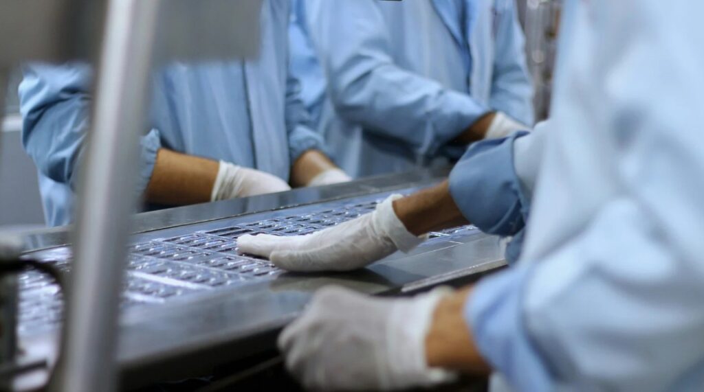 imagem com destaque para mãos enluvadas manipulando medicamentos